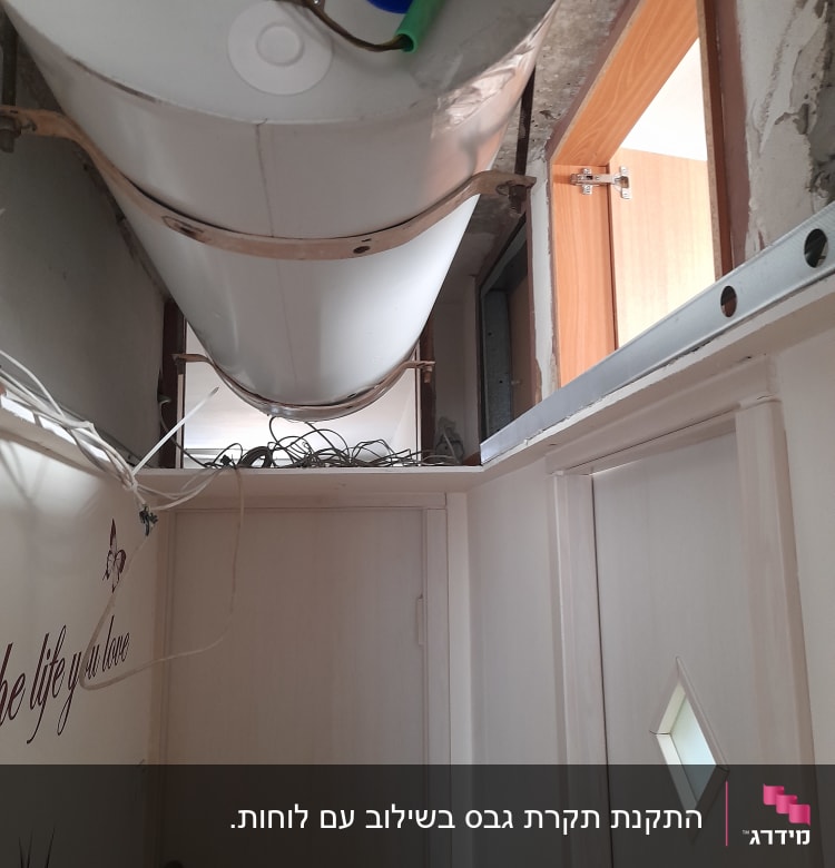 דוד מים מותקן על תקרה עם צינורות חשופים